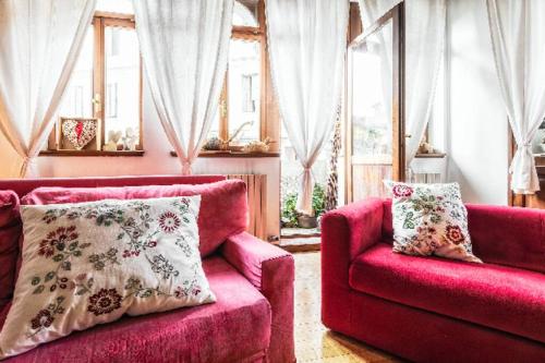 a living room with a red couch and two windows at Loft overlooking the old town . in Feltre