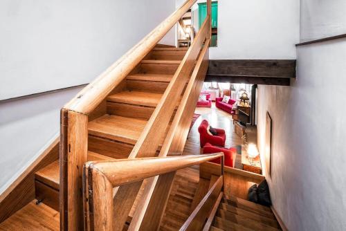 a wooden staircase in a living room with a red chair at Loft overlooking the old town . in Feltre