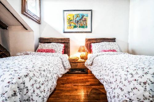 a bedroom with two beds and a table with a lamp at Loft overlooking the old town . in Feltre