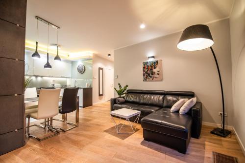 a living room with a leather couch and a table at City Lights Apartments in Kraków