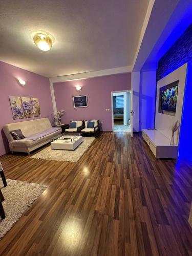 ein großes Wohnzimmer mit lilafarbenen Wänden und Holzböden in der Unterkunft Riaho Apartment in Mostar