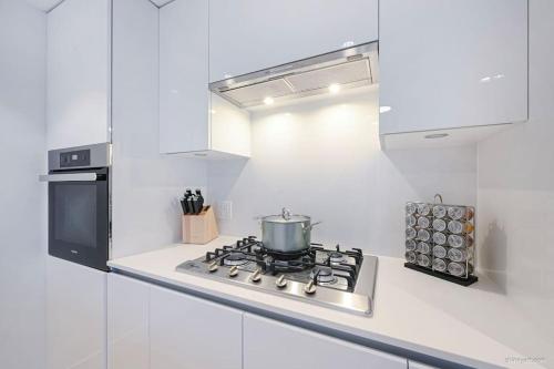 a white kitchen with a stove with a pot on it at new apartment 3 bedrooms in Richmond