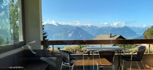 a table and chairs on a balcony with a view of mountains at Rigiana auf der Königin der Berge in Rigi Kaltbad