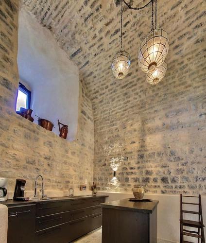 une grande cuisine avec un mur en pierre et un évier dans l'établissement Château de Sainte Jalle, à Sainte-Jalle