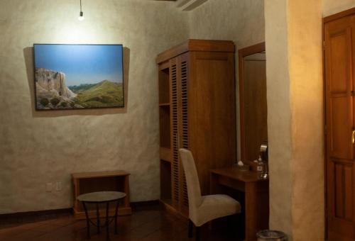 瓦哈卡德華雷斯的住宿－Hotel Boutique Casa Catrina，一间房间,配有椅子和桌子,墙上挂着一张照片