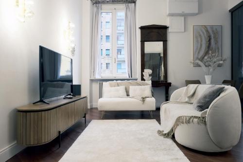 ein Wohnzimmer mit einem TV, einem Sofa und einem Stuhl in der Unterkunft ComeCasa Best View on Navigli in Mailand