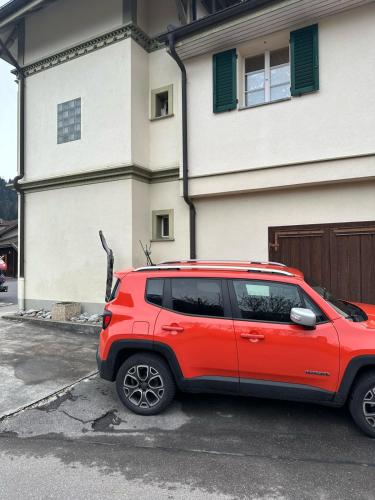a red suv parked in front of a house at Mountain Majesty Residences in Matten