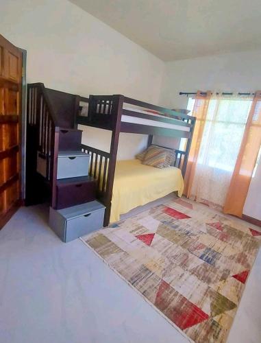 een slaapkamer met een stapelbed en een vloerkleed bij Yellow Summer in Mammee Bay
