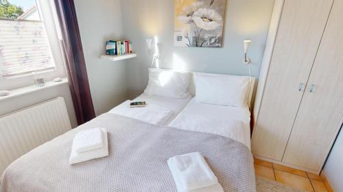 een kleine slaapkamer met een wit bed en een raam bij Feriendorf Südstrand Haus 18 in Pelzerhaken