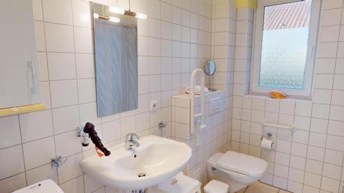 een witte badkamer met een wastafel en een toilet bij Feriendorf Südstrand Haus 18 in Pelzerhaken
