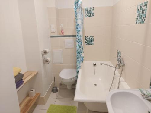 a bathroom with a tub and a toilet and a sink at Comfy apartment with 2 bedrooms in Rīga