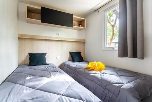 deux lits assis dans une pièce avec une fenêtre dans l'établissement Mobil-home Premium Mayotte - 3 Ch - 2 sdb, à Biscarrosse