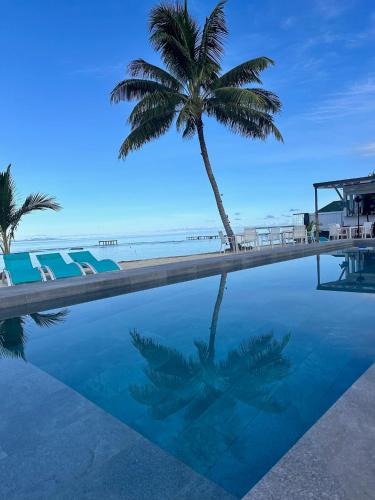 a palm tree and a swimming pool next to the beach at Pension Irivai appartement PUATOU 1 chambre bord de mer in Uturoa