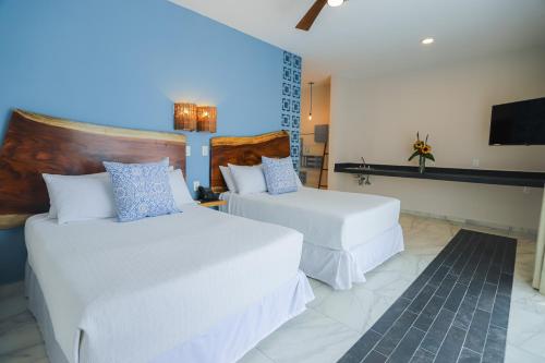 a hotel room with two beds and a flat screen tv at Luna Azul Bacalar in Bacalar