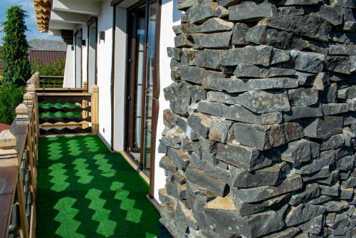 a stone wall and a green floor next to a building at La Conacul Vesel Săpânța in Săpînţa