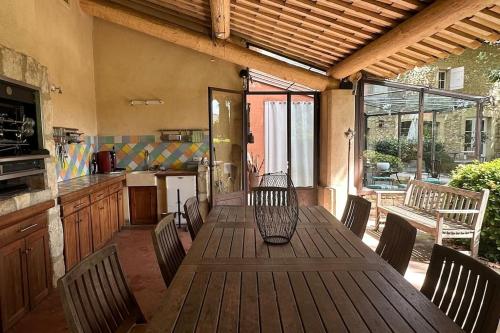 una mesa de madera con sillas en un patio con cocina en Maison avec piscine chauffée, jacuzzi et sauna 26p, en Caderousse