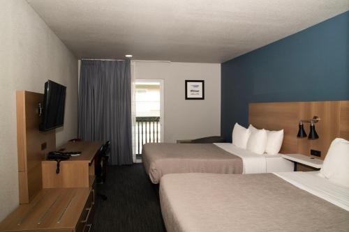 a hotel room with two beds and a television at Quality Inn Portland Airport PDX in Portland