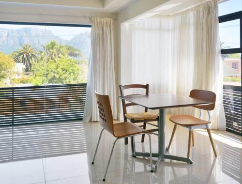 mesa y sillas en una habitación con ventana grande en The Other House - Cape Town en Ciudad del Cabo
