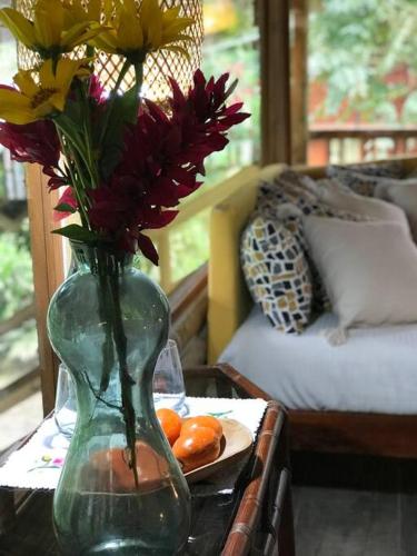 een vaas met bloemen en een bord sinaasappels op een tafel bij Casa del árbol - laVerde HABITAT 