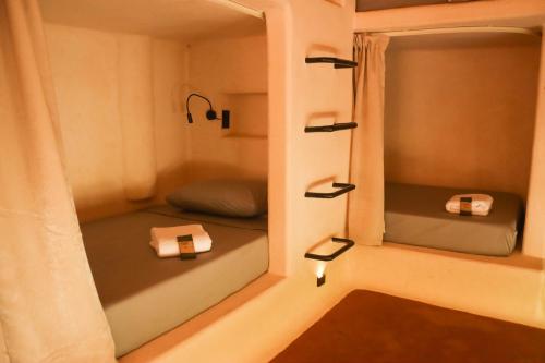 Cette petite chambre comprend 2 lits et un miroir. dans l'établissement Secret Beach Hostel, à Puerto Escondido