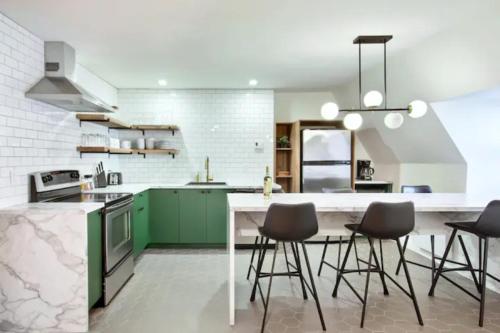a kitchen with green cabinets and bar stools at Golden Cross // Typical old Quebec appartement in Quebec City