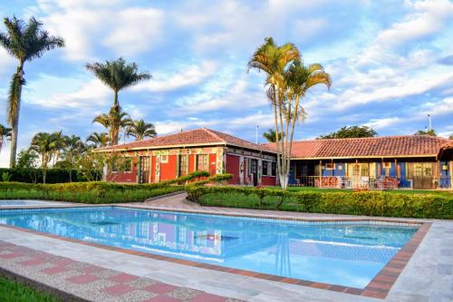 een huis met een zwembad en palmbomen bij hotel villa nazareth in Quimbaya