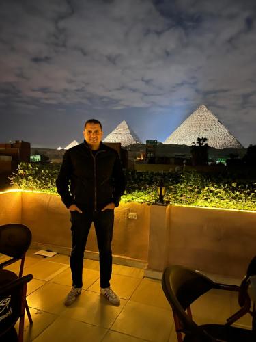 a man standing on a roof with pyramids in the background at Badr pyramids inn in Cairo