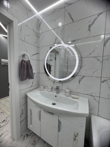 Baño blanco con lavabo y espejo en Квартира - студия 72 кв.м, en Uralsk