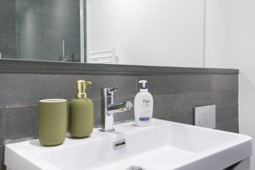 a bathroom sink with two bottles and a mirror at The Vale - Luxury Apartments in London