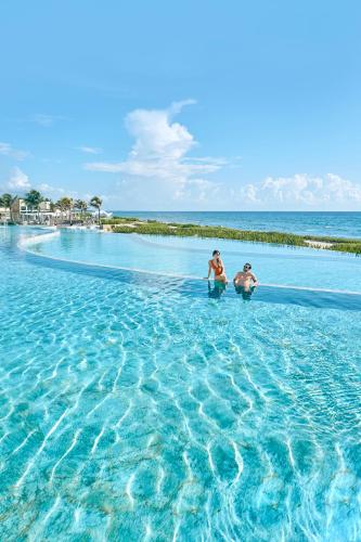two people standing in the water at the beach at TRS Yucatan Hotel - Adults Only in Akumal