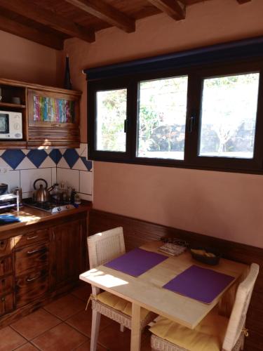 una cucina con tavolo in legno e 2 finestre di Casa Palmera y Casa Dátil a Haría