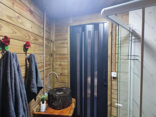 a bathroom with a shower and a wooden wall at Casa na Árvore - Chalé Quemeninho in Apiaí