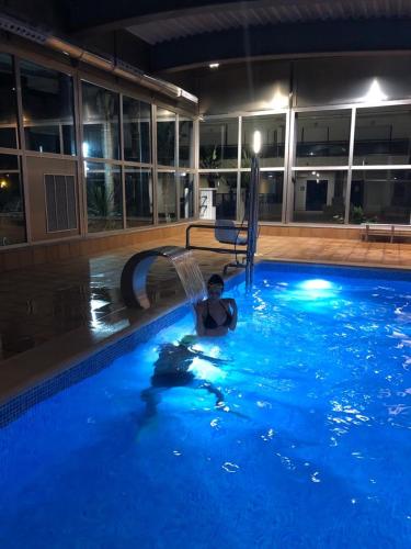 a man is in a swimming pool at night at Apartamento El Eden in Playa de Gandia