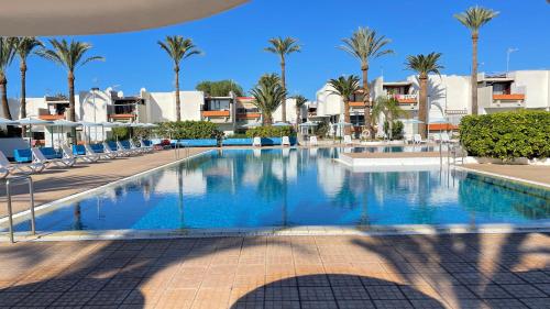 una piscina in un resort con palme e edifici di Primavera a Costa Del Silencio