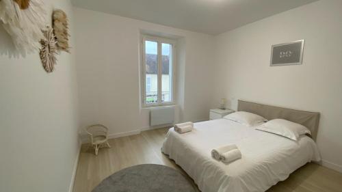 a white bedroom with a large bed with two pillows at Le Grand Rambolitain in Rambouillet