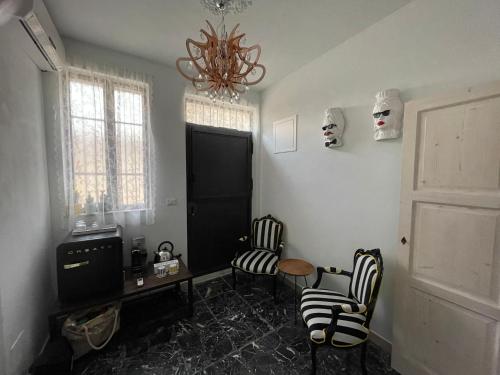 een woonkamer met stoelen en een tafel en een kroonluchter bij Macallè Suite Noto, charme e relax con giardino in Noto