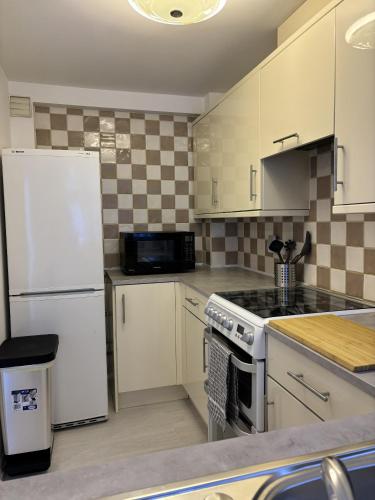 a kitchen with white cabinets and a white refrigerator at Cosy Corner - 2 bed house with parking! in Southampton