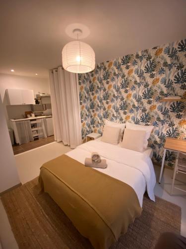 um quarto com uma grande cama branca e papel de parede florido em Joli studio centre historique et au calme (2) em Montpellier