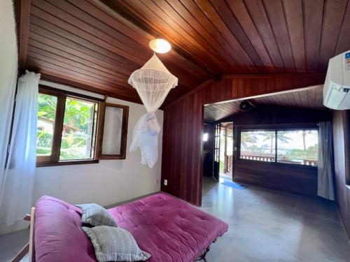 uma grande cama roxa num quarto com tecto em madeira em Casa do João na Ilha de Boipeba