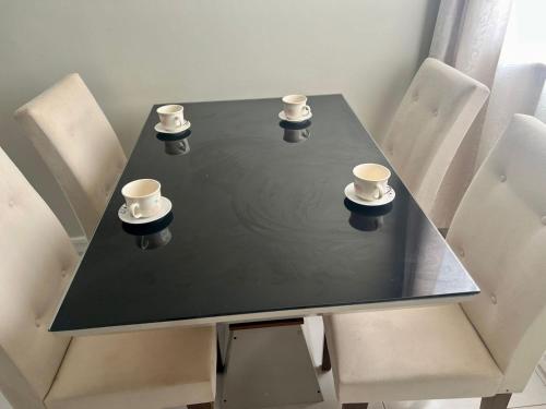 a black table with three cups and chairs at Apartamento Charmie in São Luís