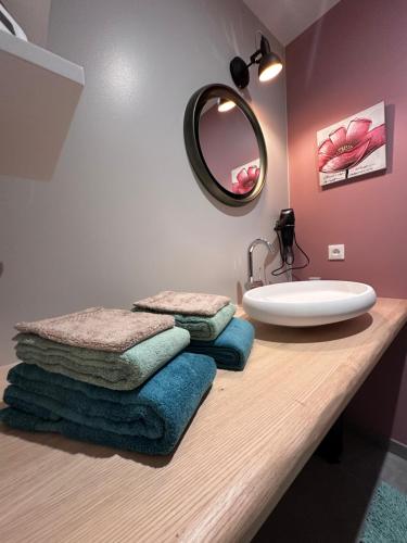a bathroom with a sink and towels on a counter at Maison d hôtes SPA Pivoine et Colibri in Domfessel