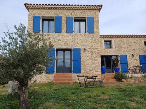 une maison avec des volets bleus et une table devant elle dans l'établissement La maison aux volets bleus, à Tresques