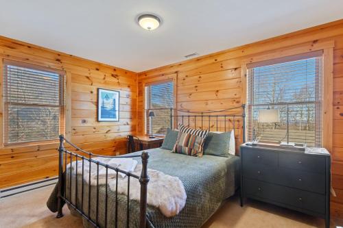 1 dormitorio con cama, paredes y ventanas de madera en Big Bear Escape, en Beech Mountain