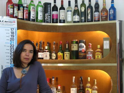 a woman sitting at a bar with bottles of alcohol at B&B Itala in Recanati