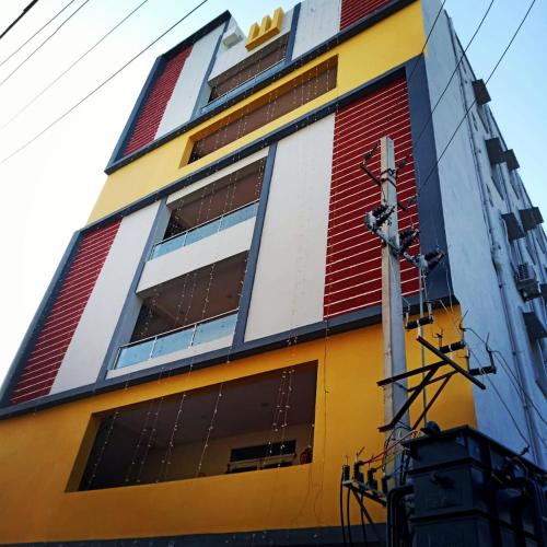 een geel en rood gebouw met een paal ervoor bij SNEHA INN in Mancherāl