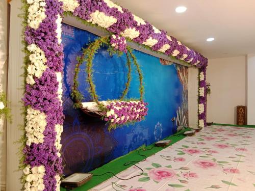 een podium bedekt met paarse en witte bloemen bij SNEHA INN in Mancherāl