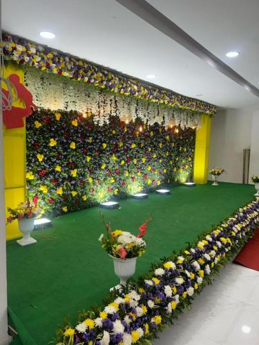 een kamer met een groene vloer met bloemen en verlichting bij SNEHA INN in Mancherāl