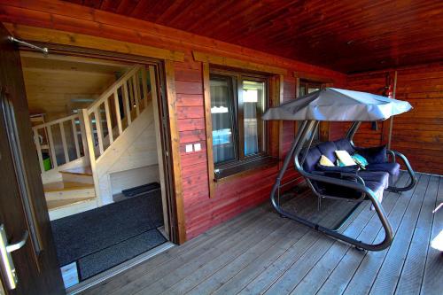 eine Veranda einer Hütte mit einem Stuhl und einem Sonnenschirm in der Unterkunft Ośrodek Wypoczynkowy IDA in Mielenko