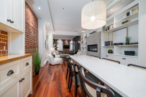 a kitchen with white cabinets and a bar with chairs at -NEW- The Rock and Red Luxury Condo in Quebec City