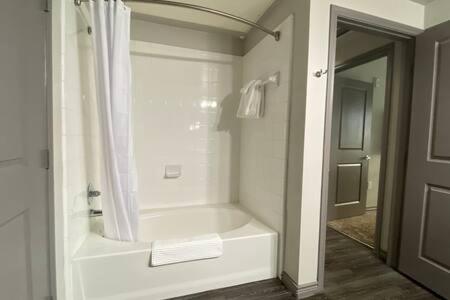 a white bathroom with a shower and a tub at KING BEDS & Patio-65 inch Roku-Walk to Food and Drinks in Fort Worth